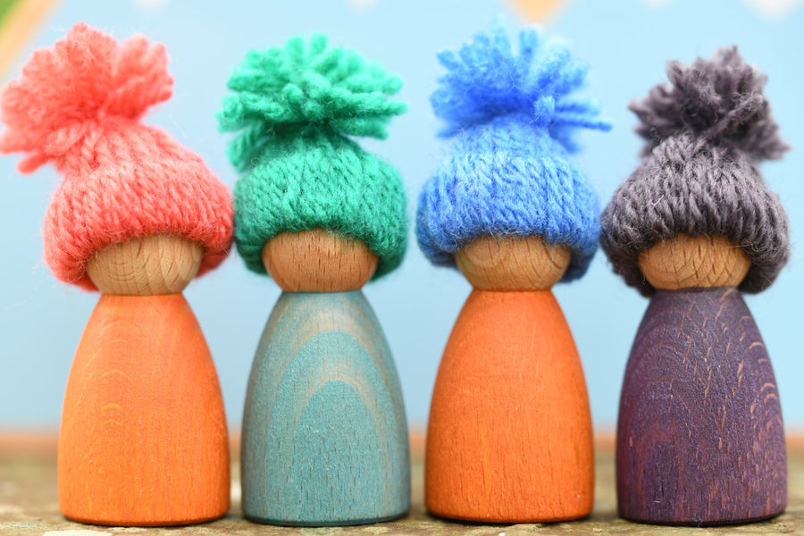 A group of 4 peg dolls each wearing a handmade woolly hat