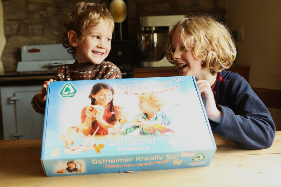 Two children hold up the Ostheimer Creative Painting Set at a kitchen table