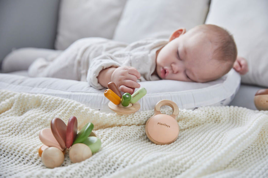 A baby fast asleep grasping the PlanToys Flexi Jellyfish Grasping Toy