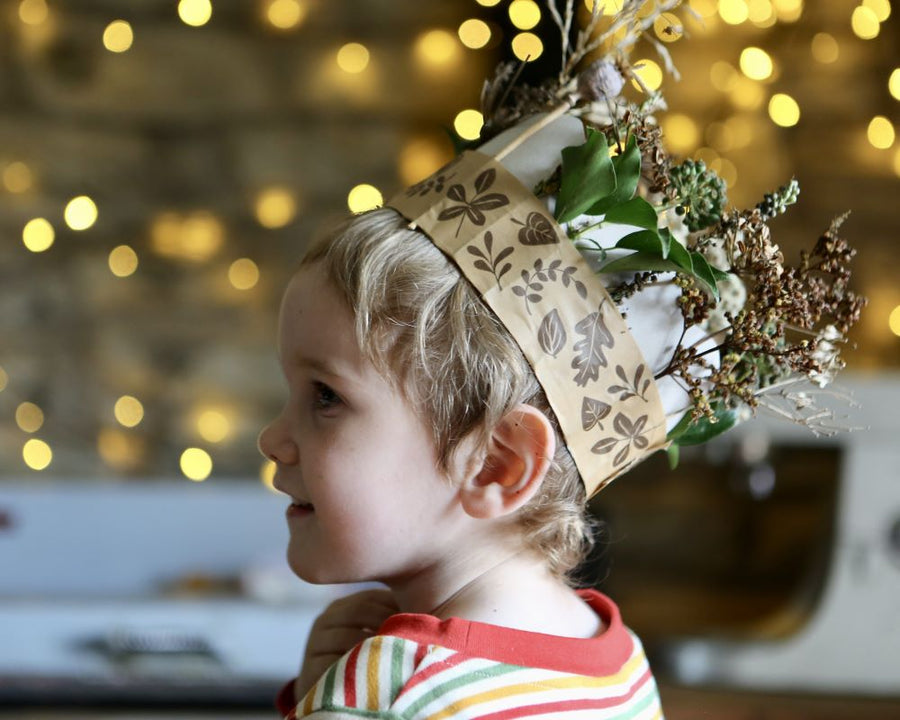 Child wearing a Winter Crown, a winter craft for kids made using paper tape, recycled card and dried seed heads