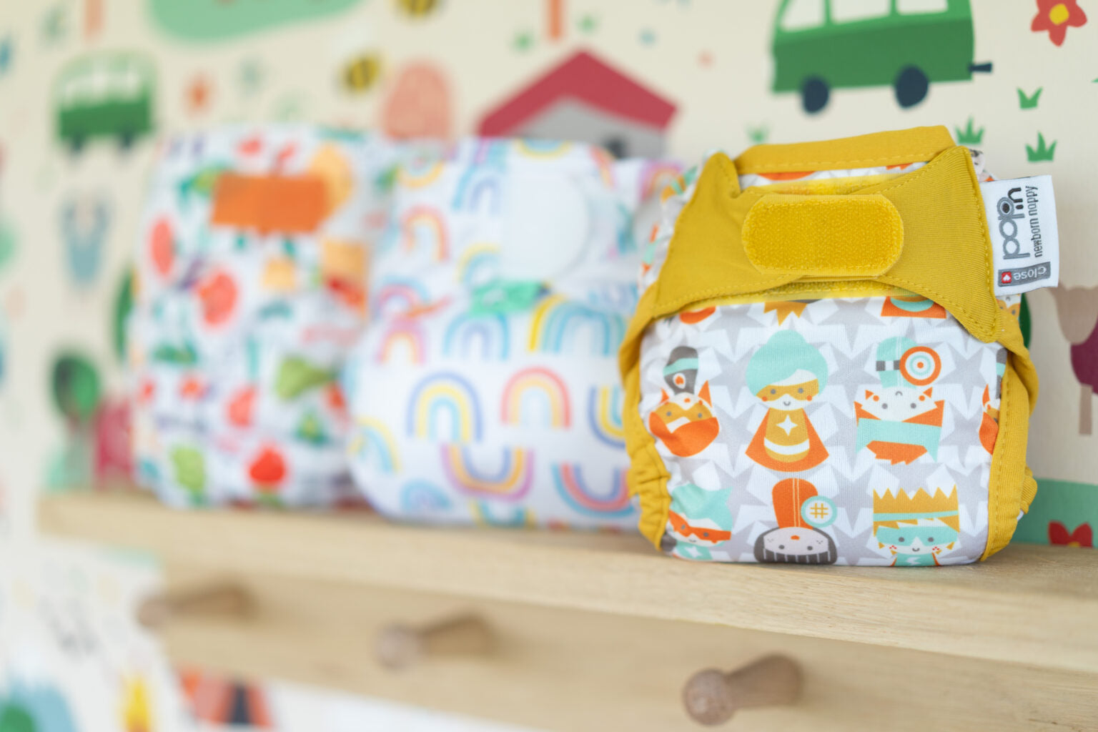 3 reusable nappies lined up on a wooden shelf