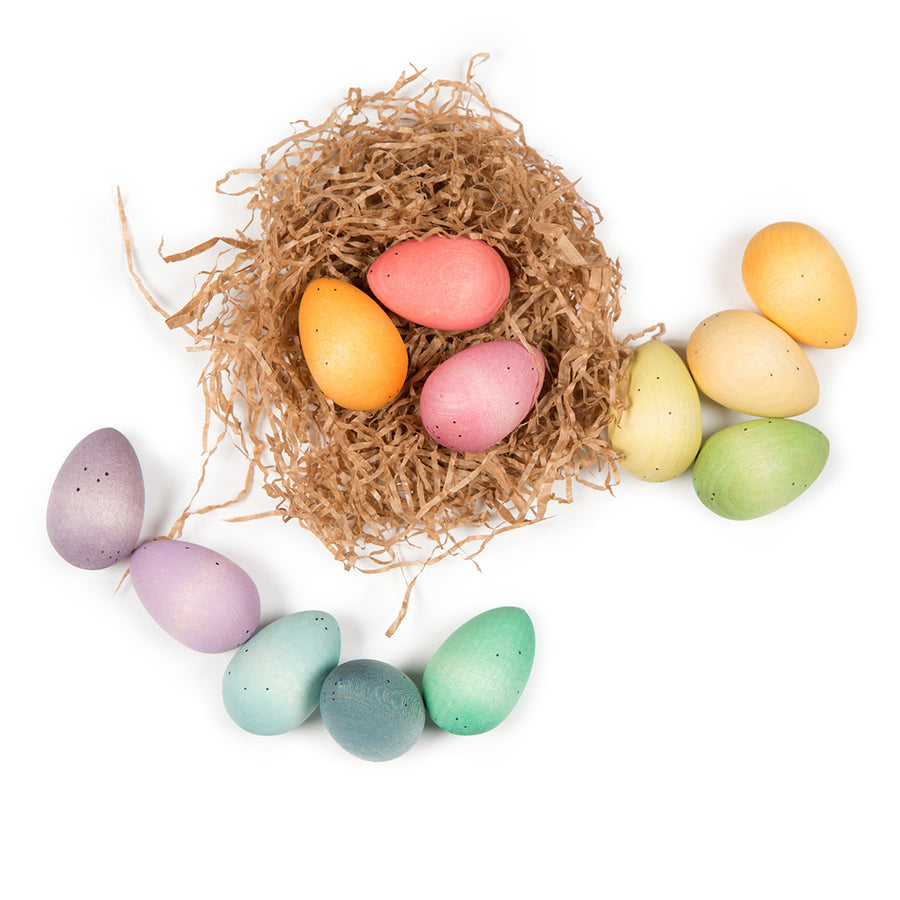 three wooden grapat happy eggs in the paper nest with some scattered around