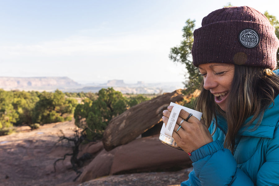 A collection of Kleen Kanteen 12oz Camping Mugs stacked on top of a rock