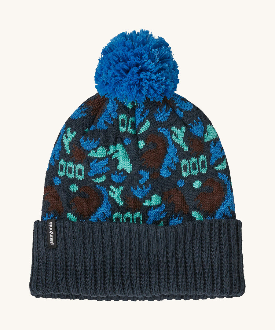 A blue Patagonia bobble beanie with different shapes and patterns on a cream background.