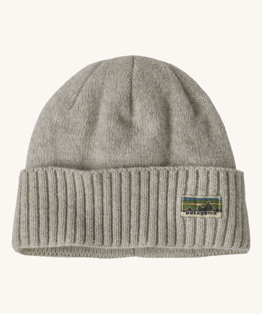 A grey beanie with the Patagonia logo on the front on a cream background