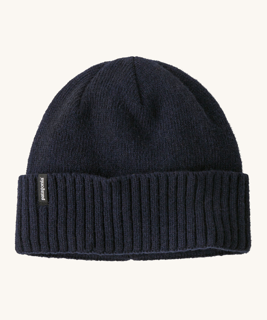 A navy beanie with the Patagonia logo on the front on a cream background.