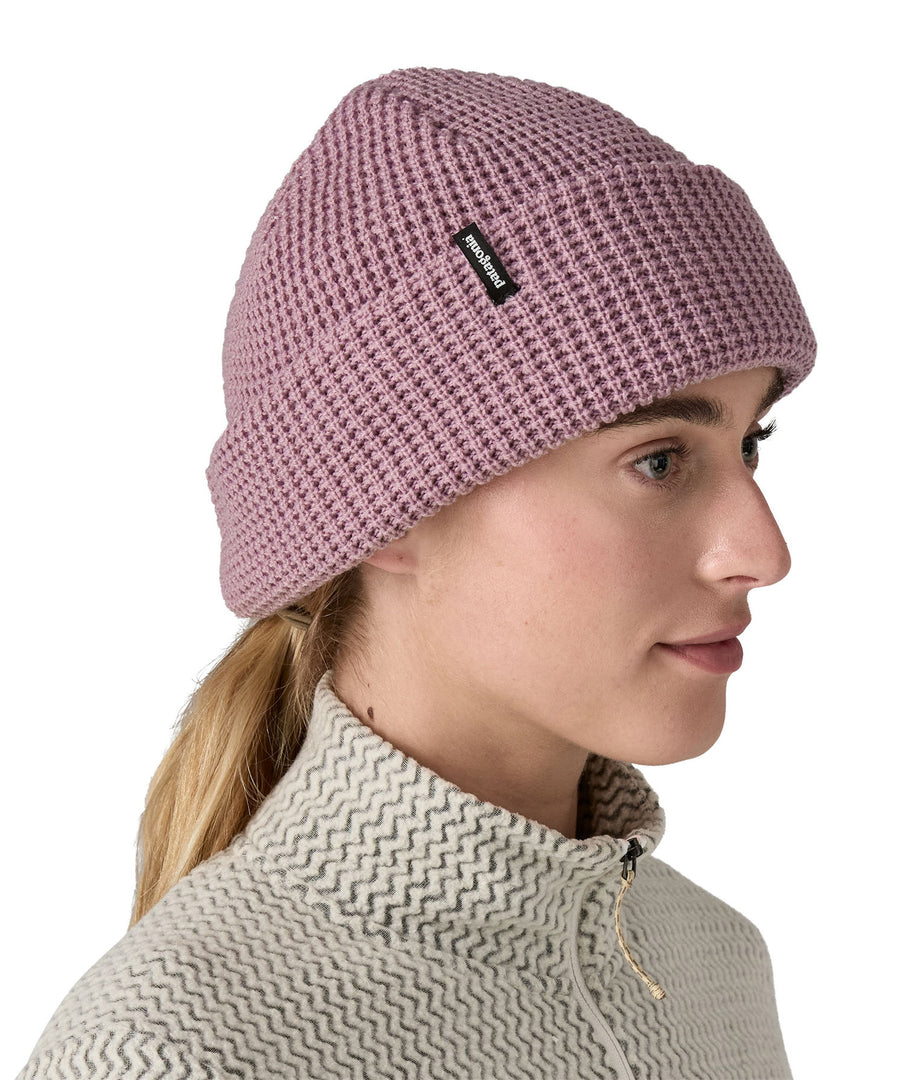 A female adult wearing the plain light pink Patagonia beanie.