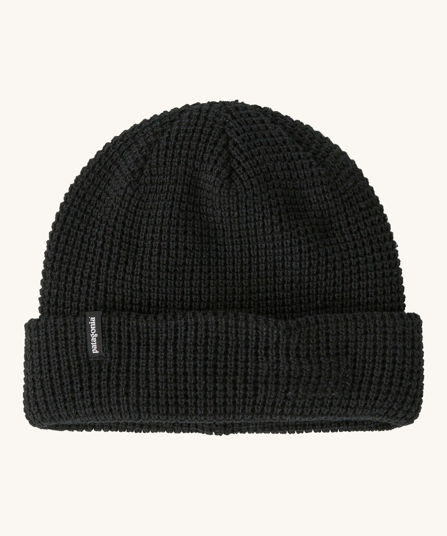 A plain black Patagonia beanie on a cream background.