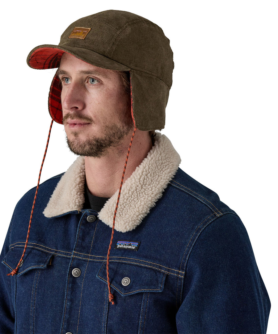 A male adult wearing the brown Patagonia earflap cap with the flaps down.