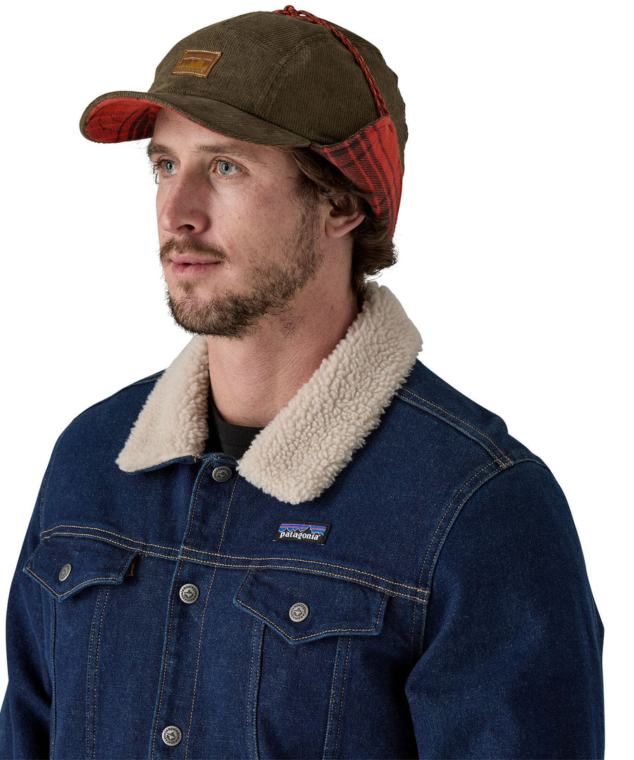 A male adult wearing the brown Patagonia earflap cap with the flaps tied up.