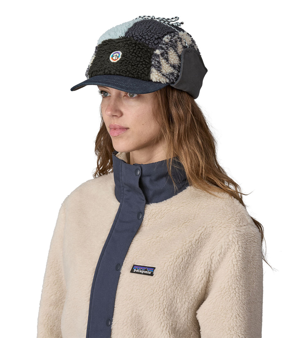 A female adult wearing the blue fleeced Patagonia earflap cap with the flaps up