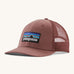 A pink Patagonia trucker hat with the Patagonia logo on the front on a cream background