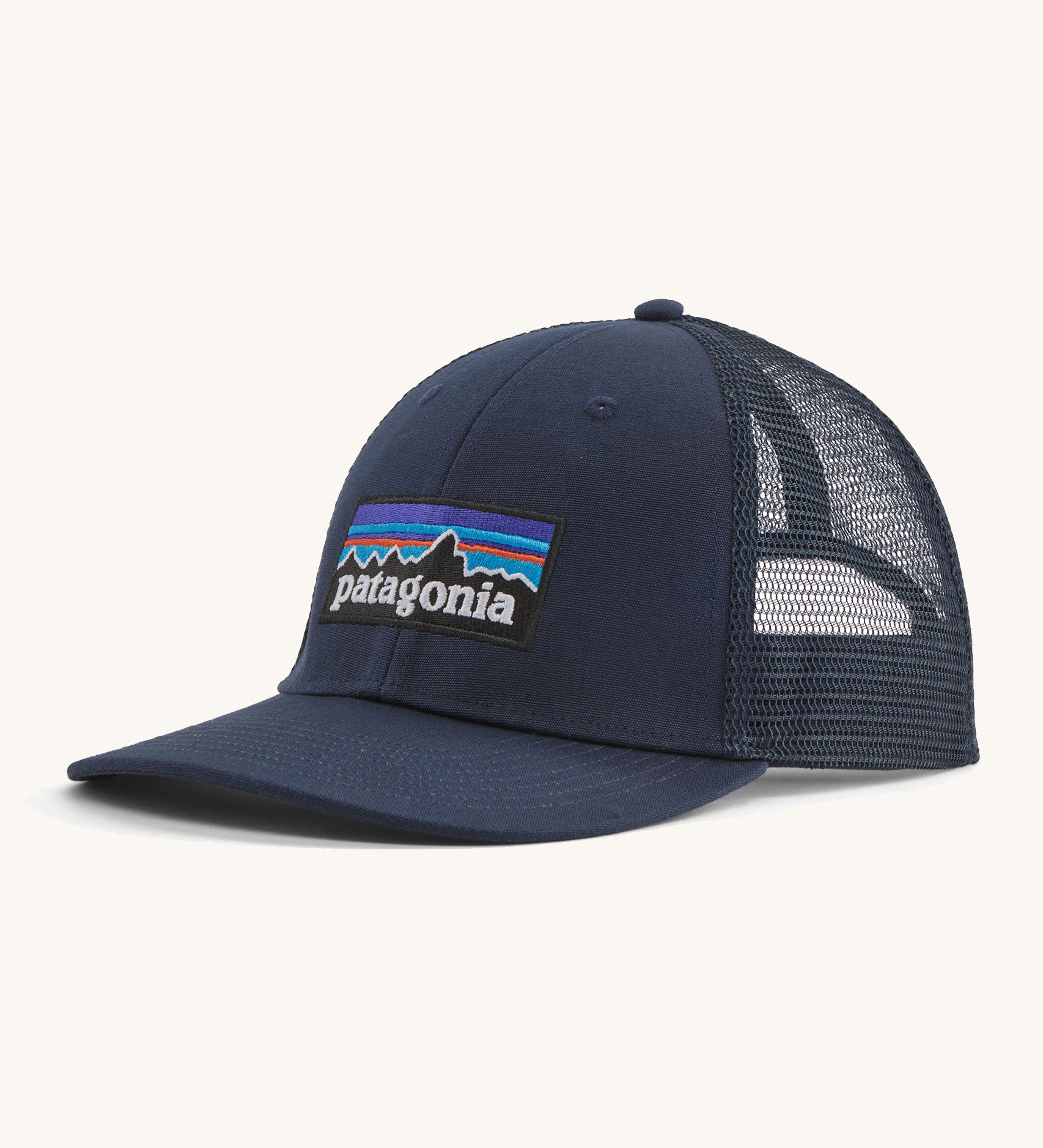 A navy Patagonia trucker hat with the Patagonia logo on the front on a cream background.