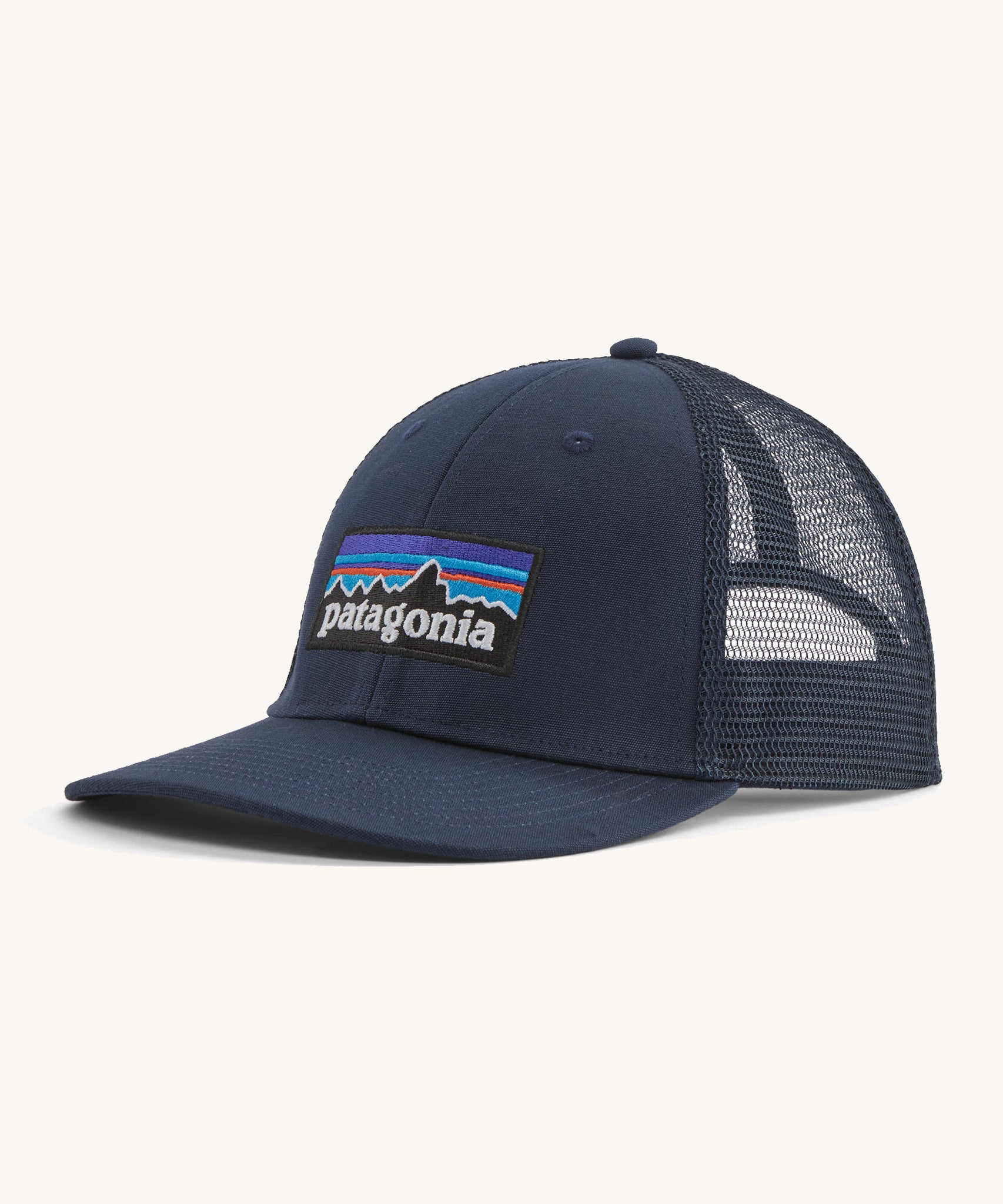 A navy Patagonia trucker hat with the Patagonia logo on the front on a cream background.