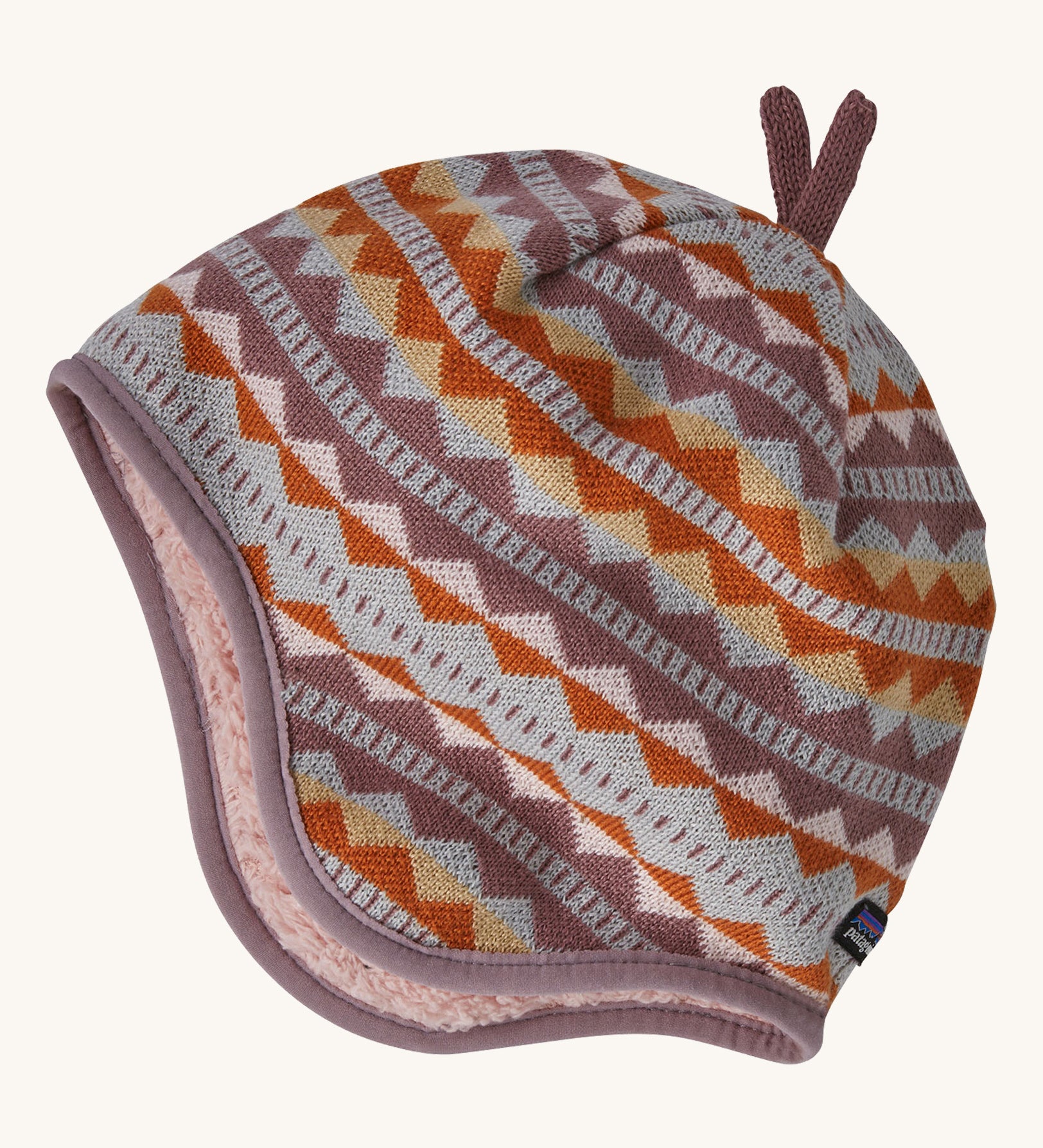 A light coloured reversible beanie with a diamond design on a cream background.