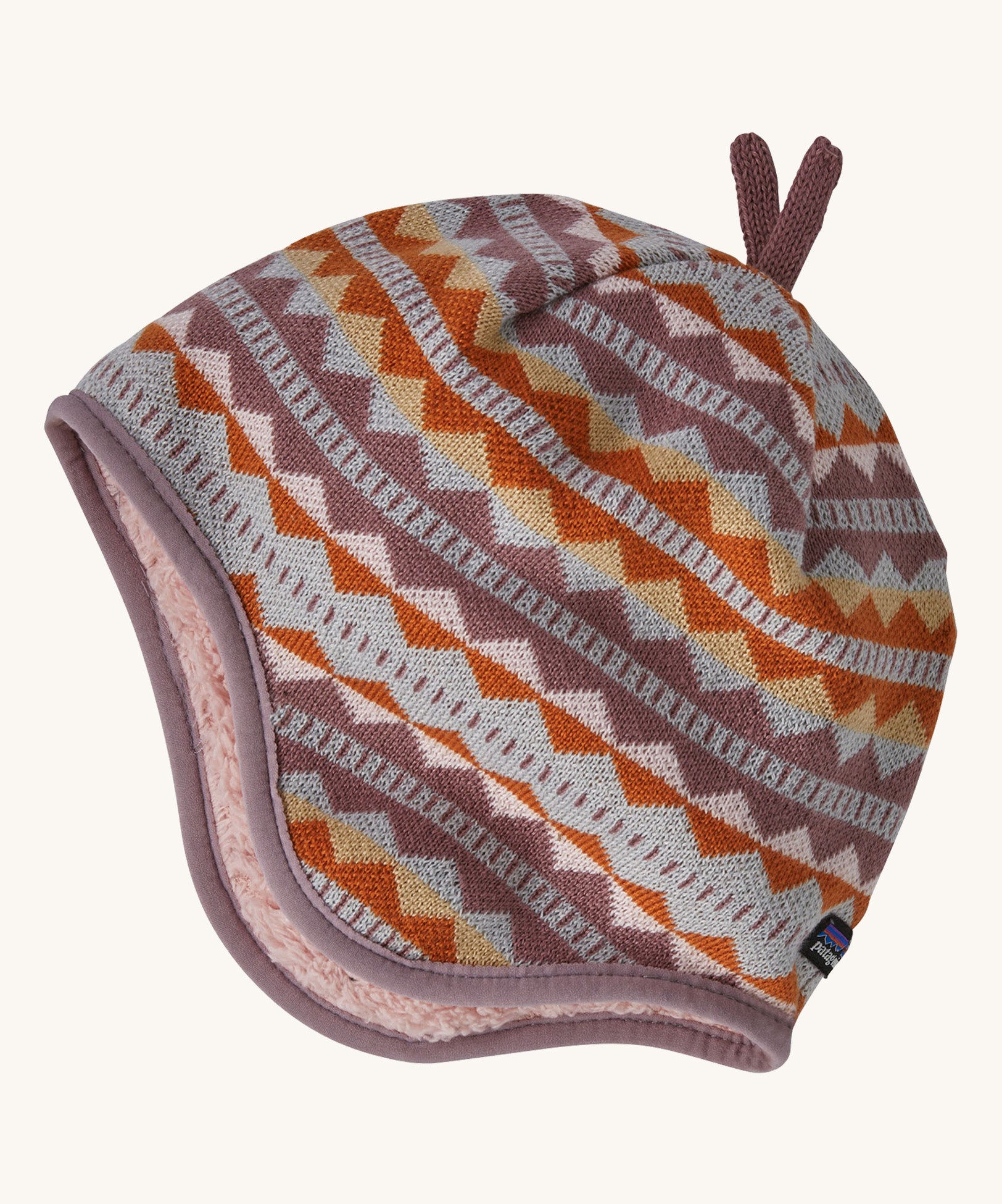 A light coloured reversible beanie with a diamond design on a cream background.