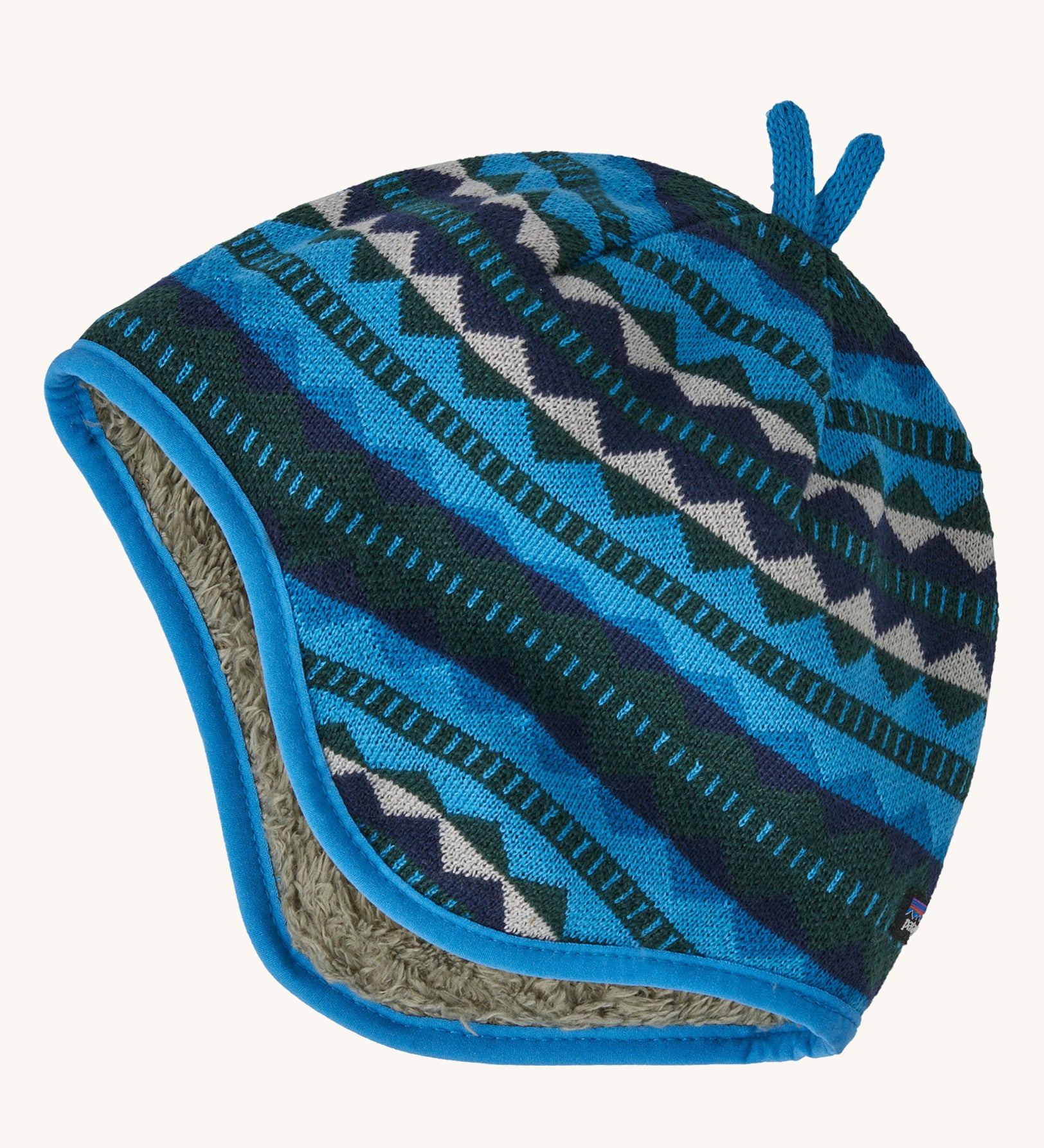 A blue reversible beanie with diamond patterns on a cream background