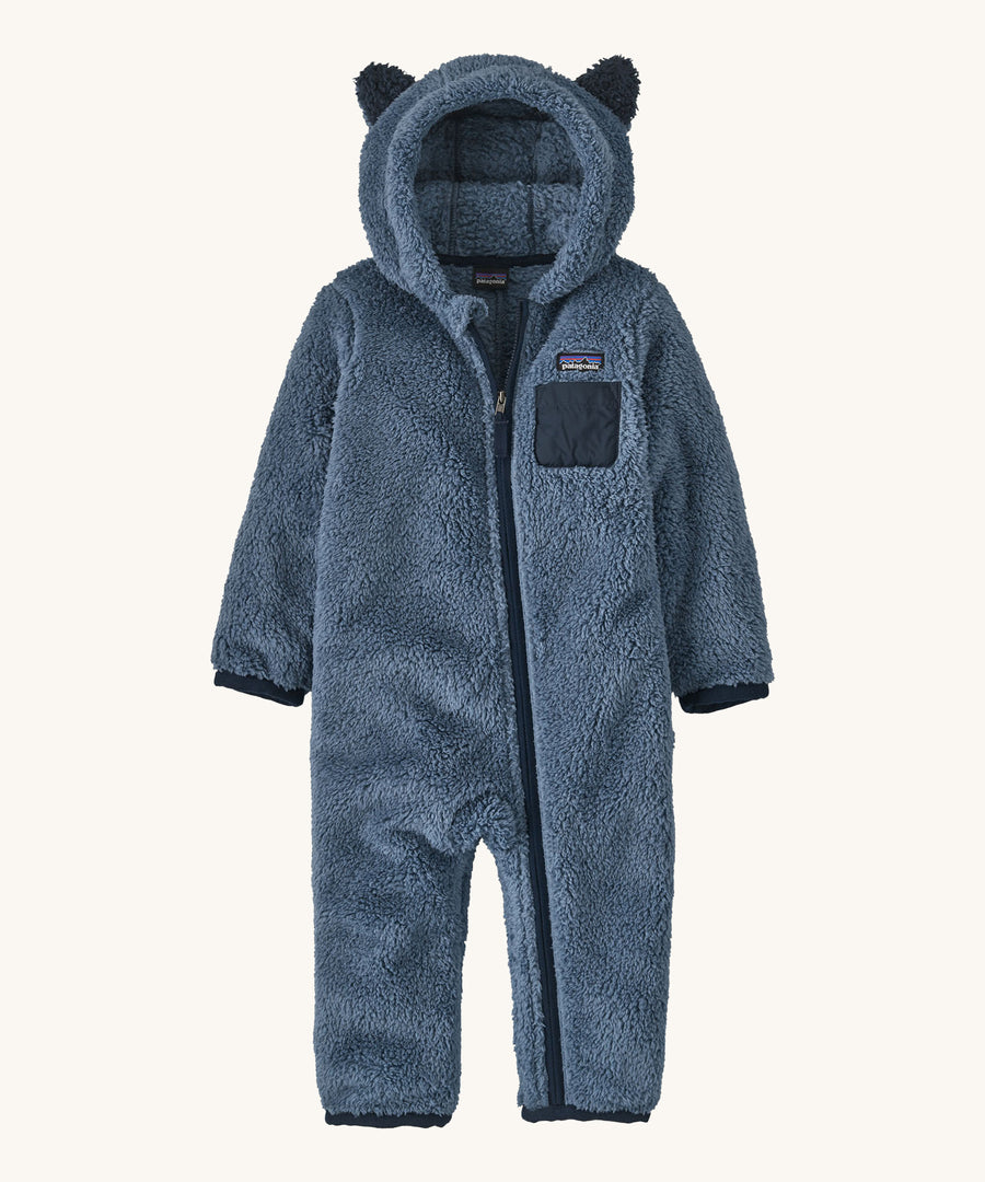 Dark blue fluffy kids all in one with little ears on the hood on a cream background