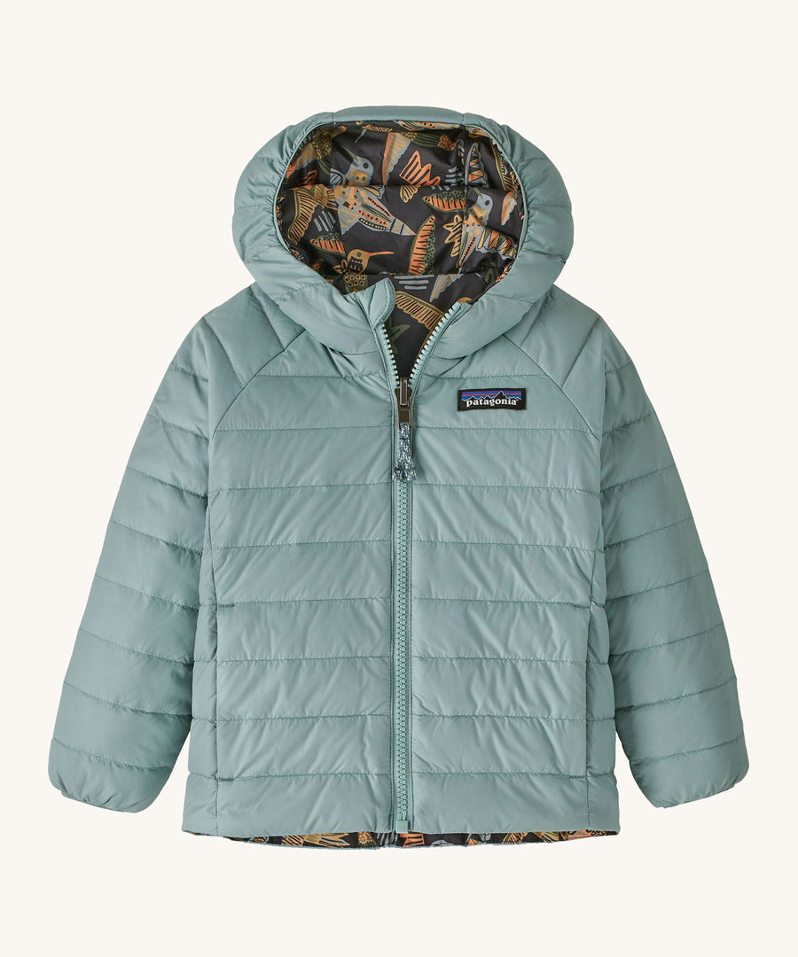 Light green with reversible bird print Patagonia down jacket on a cream background