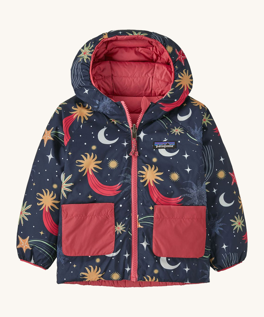 Navy Patagonia reversible jacket with a moon and stars design and red pockets on a cream background