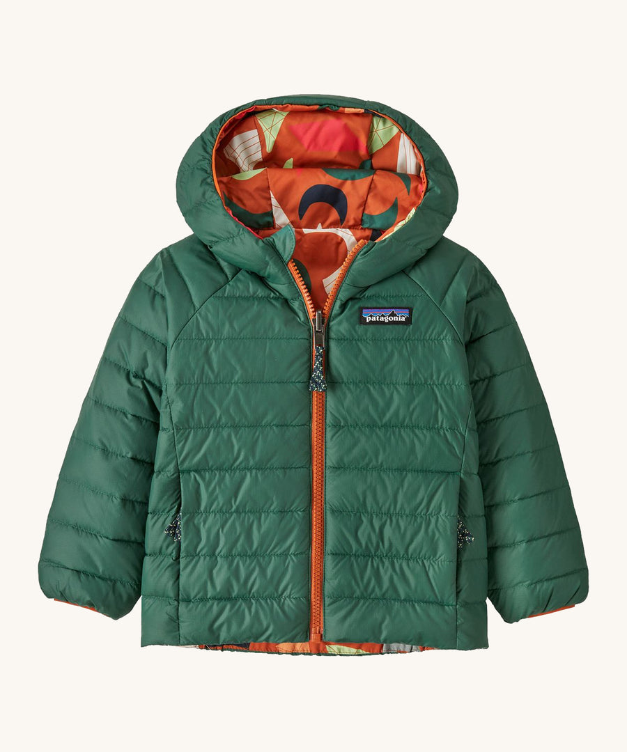 Green Patagonia reversible jacket with a abstract design on the hood on a cream background