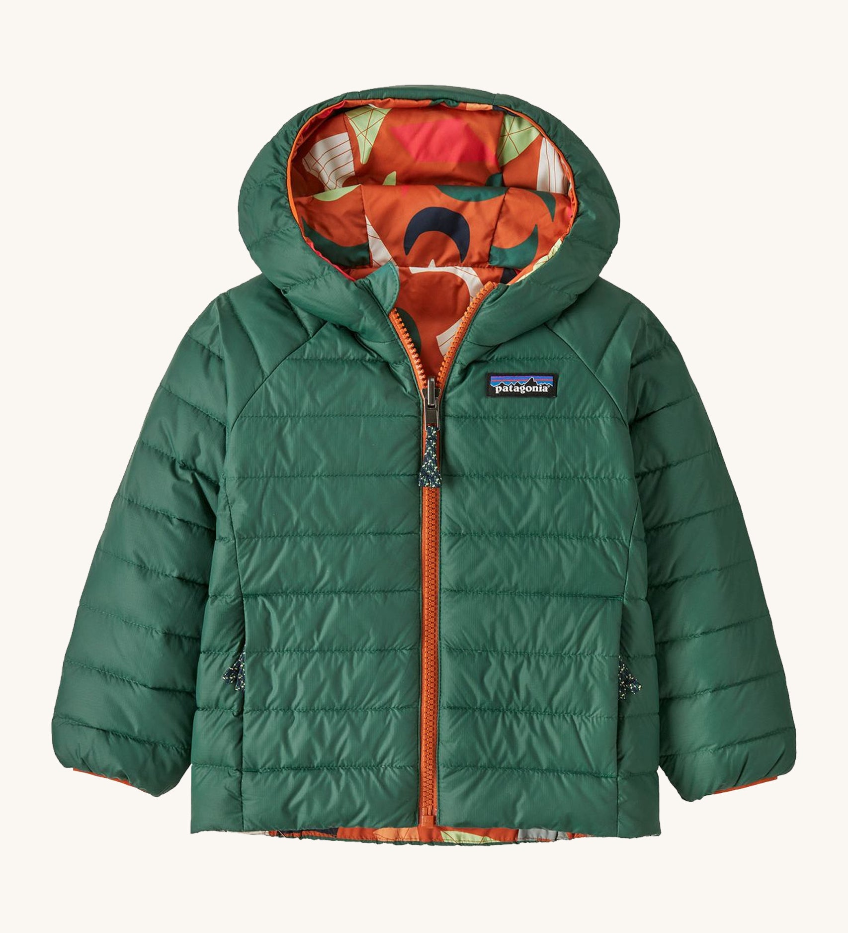 Green Patagonia reversible jacket with a abstract design on the hood on a cream background