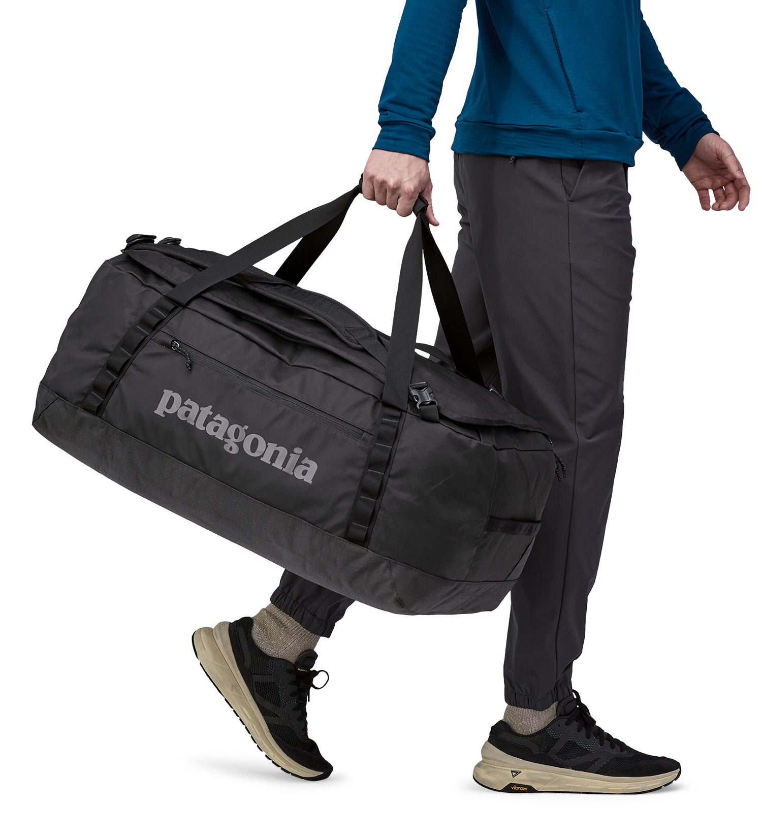 A person carrying the Patagonia Black Hole Duffel 70L Black with the carry handles