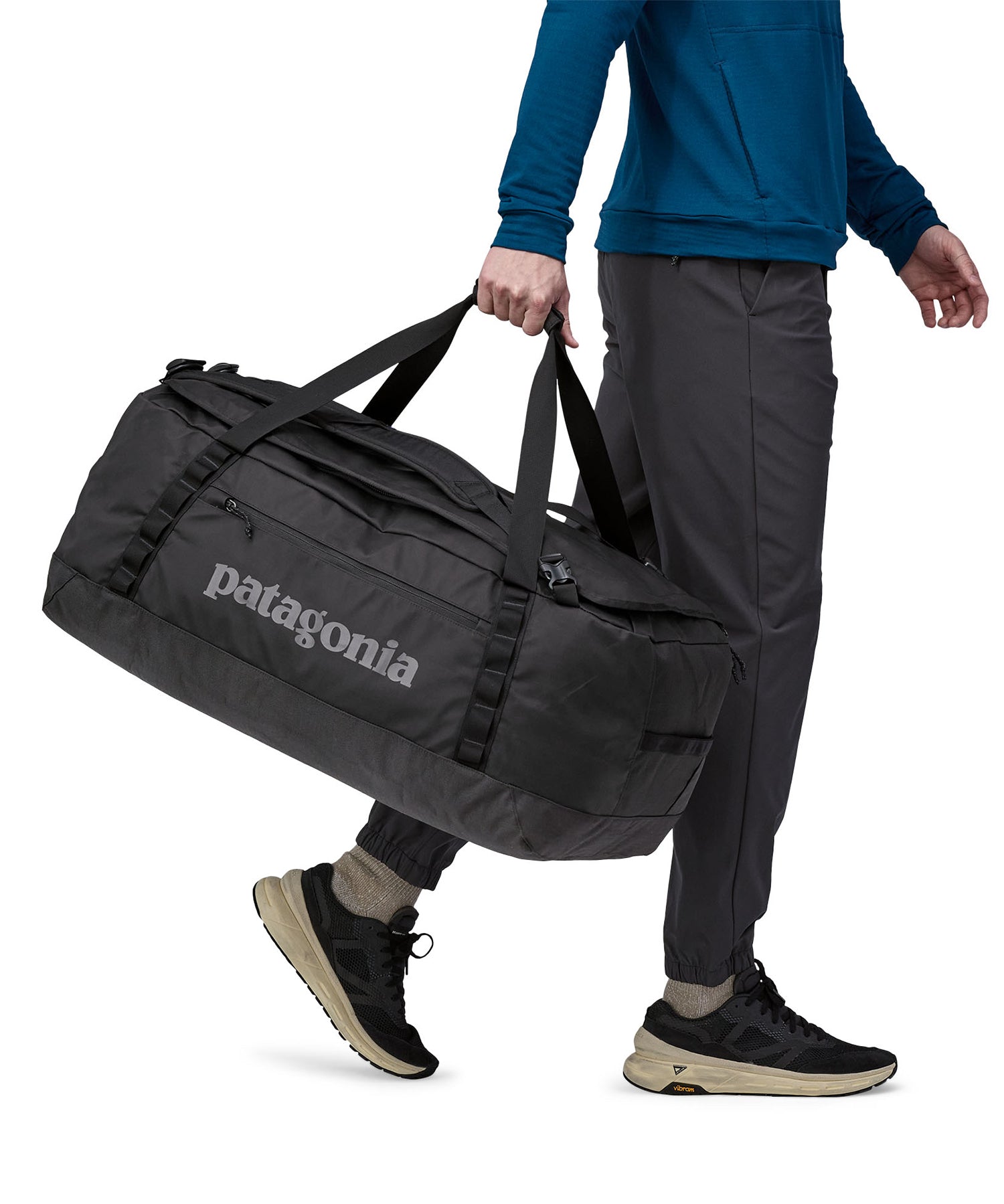 A person carrying the Patagonia Black Hole Duffel 70L Black with the carry handles