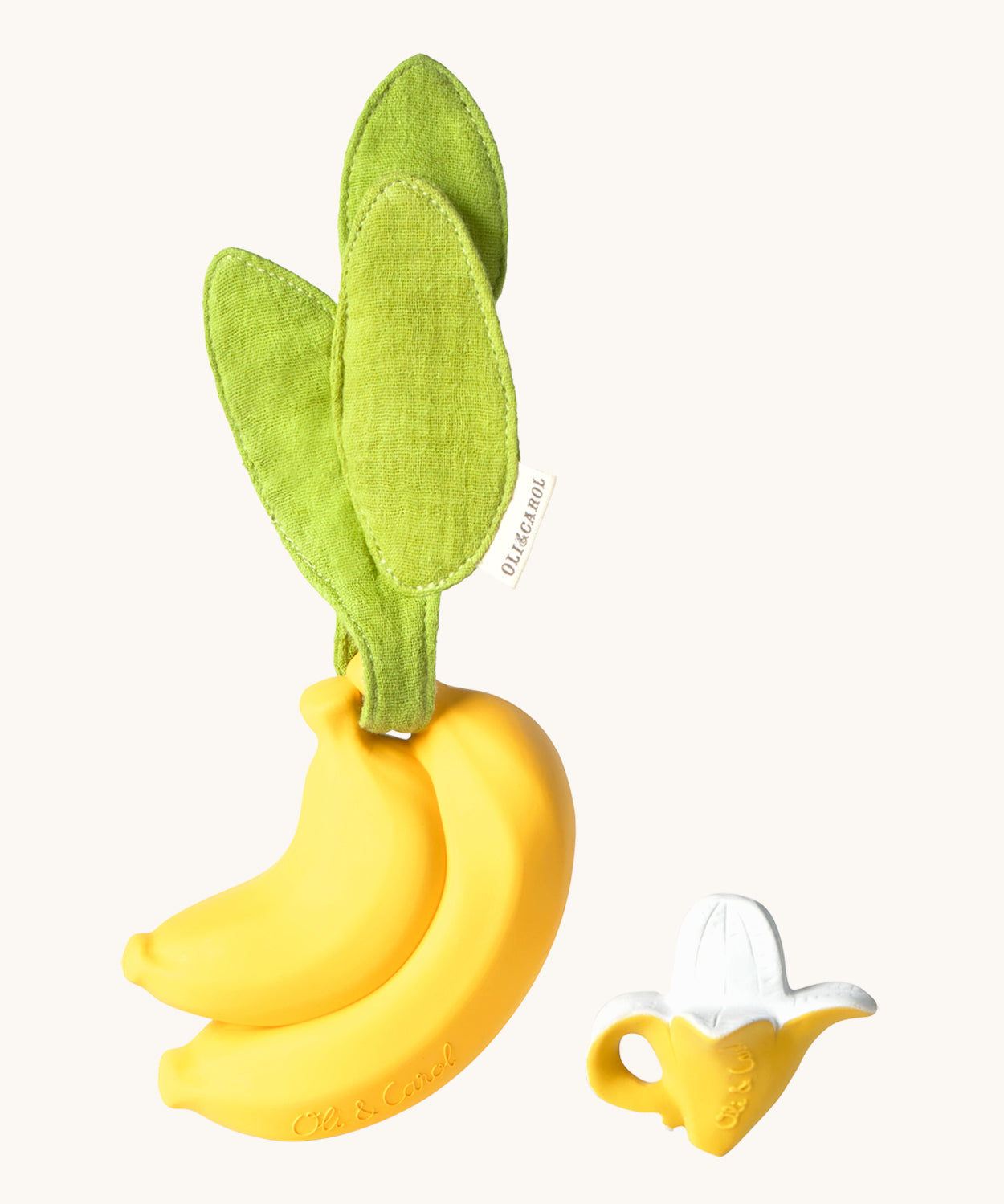 The Ana Banana Pacifier Holder on a cream background. The image shows an Oli & Carol banana teething toy next to the holder. The banana is smooth and has a green muslin leaf attachment on the top to tie the holder to a pram handle, high chair etc.