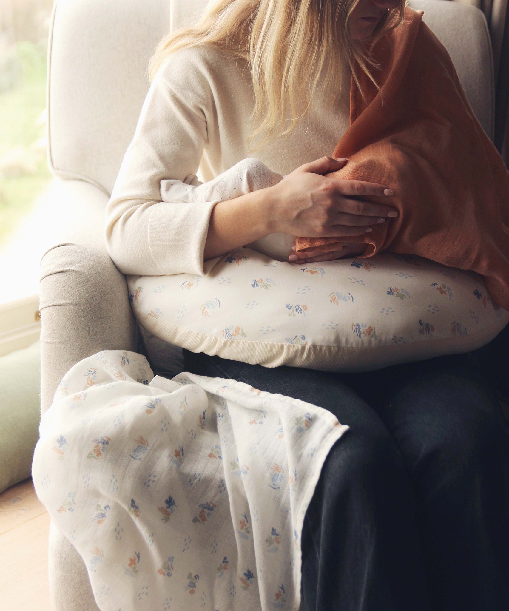 Avery Row Nursing Pillow - Coastline, a mother breastfeeding her baby with a brown muslin cover.