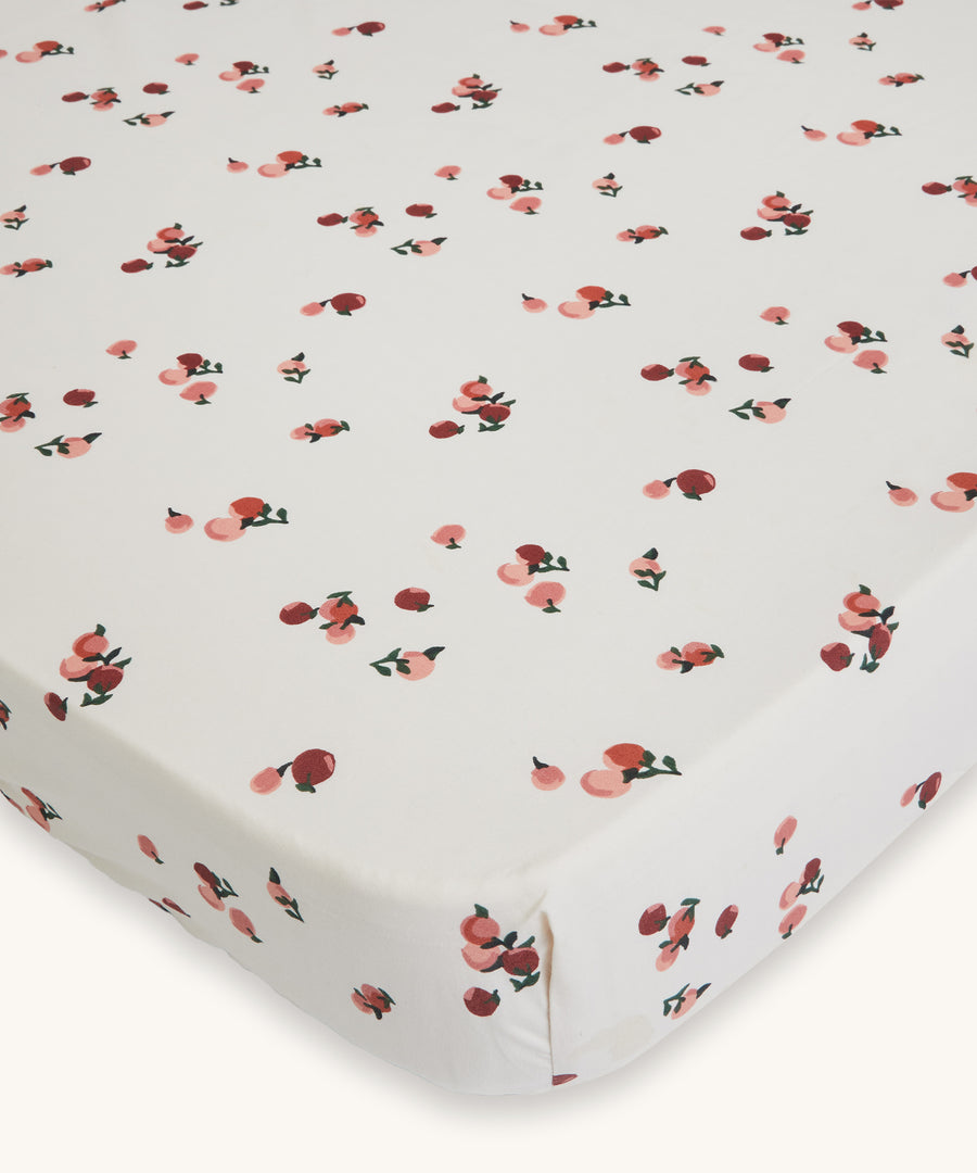 Avery Row Cotbed Fitted Sheet - Peaches. A light cream sheet with delicate peach print