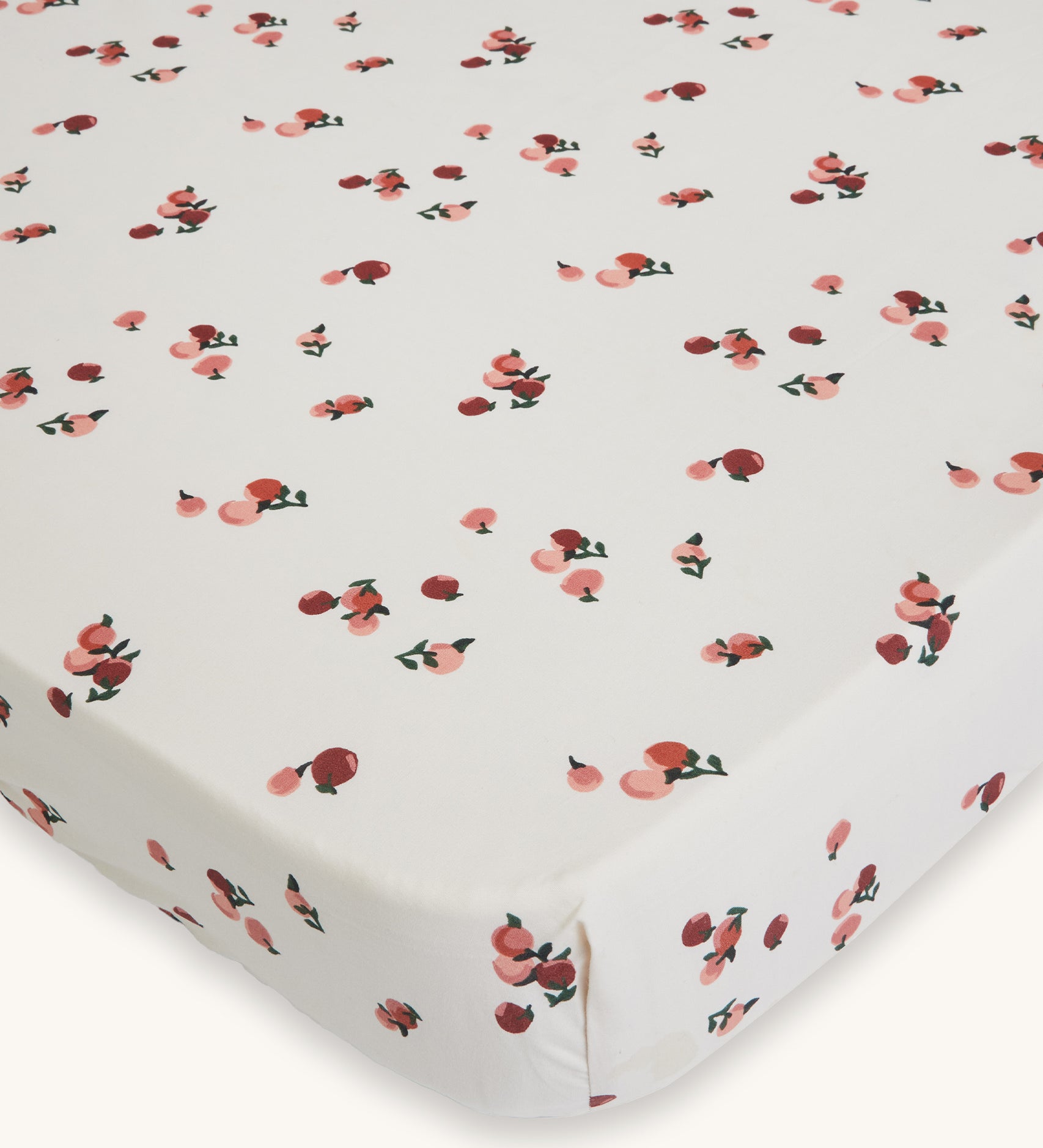 Avery Row Cotbed Fitted Sheet - Peaches. A light cream sheet with delicate peach print