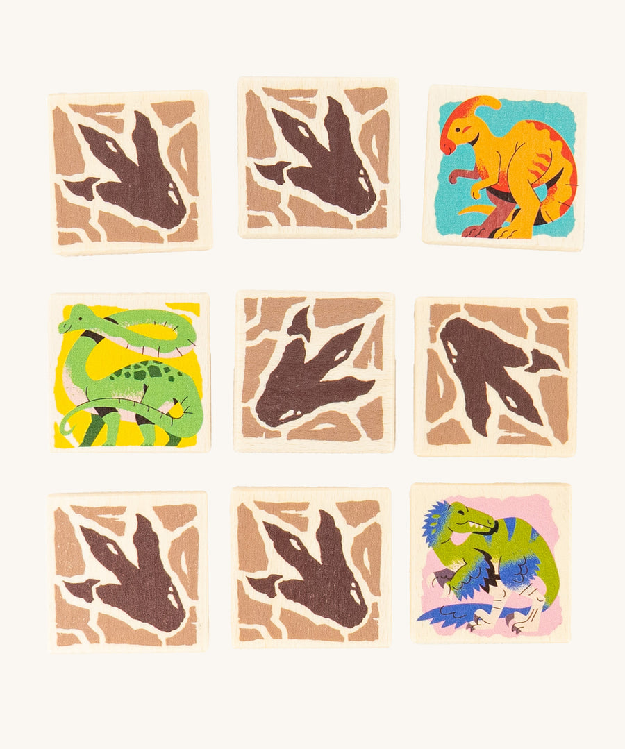 9 square pieces from the Bajo Dinosaur Memory Game showing 3 with dinosaur images and 6 with dinosaur foot prints. The footprints are on the back of the blocks and the dinosaur images are on the side that needs to be matched with the same image