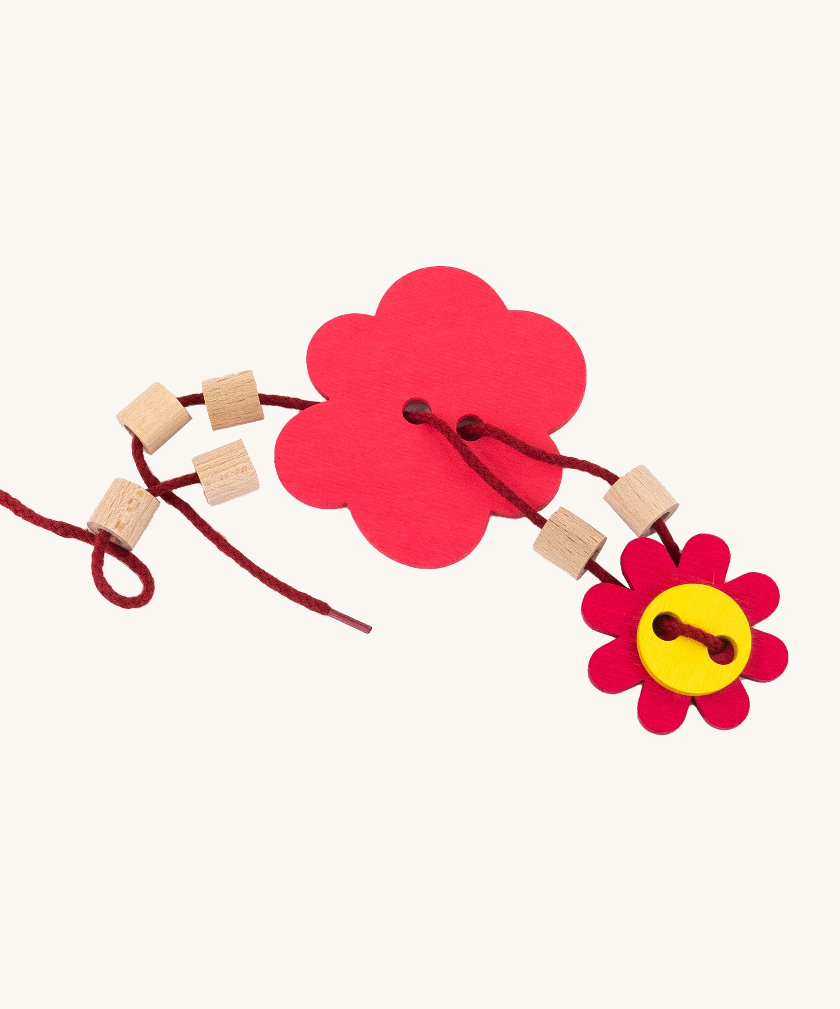 A red lace with wooden beads and flower shaped disks from the Bajo Wooden Lacing Toy - Flower Meadow, showing how to attach the pieces together, on a cream background