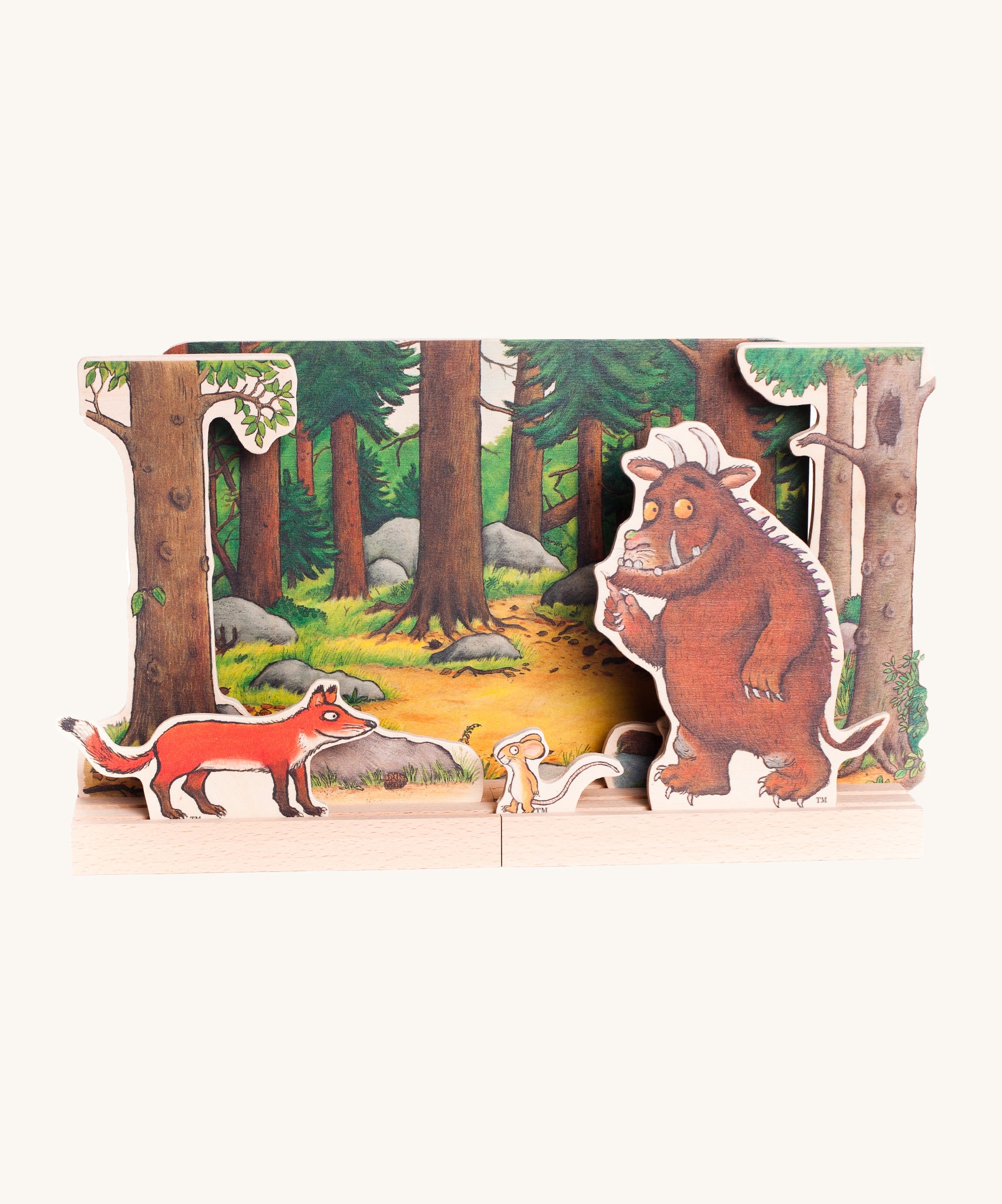 Bajo Gruffalo Wooden Theatre showing the woodland backdrop, Gruffalo, Muse and Fox characters set inside wooden boards with small grooves to hold the figures in place. The image is on a cream background