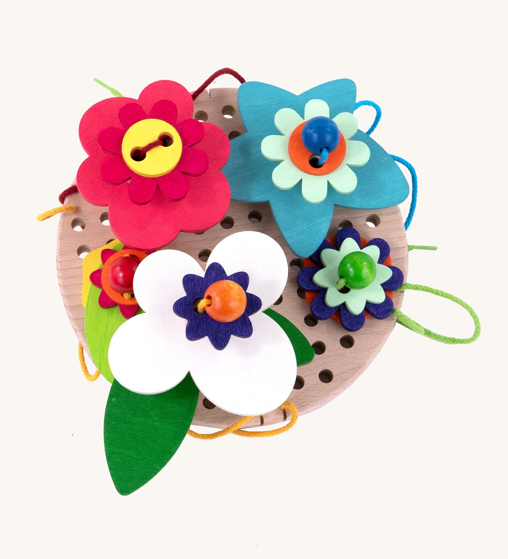 A top down view of the Bajo Wooden Lacing Toy - Flower Meadow. The image shows different shaped wooden flowers disks, threaded together with beads and colourful laces onto a wooden board with holes to allow the laces to go through. The image is on a cream background