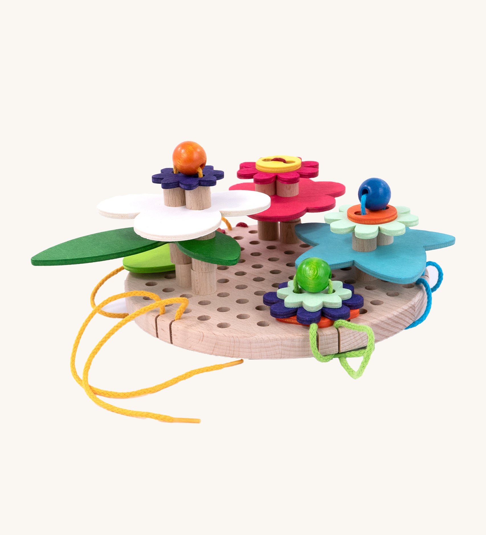 A side down view of the Bajo Wooden Lacing Toy - Flower Meadow. The image shows different shaped wooden flowers disks, threaded together with beads and colourful laces onto a wooden board with holes to allow the laces to go through. The image is on a cream background