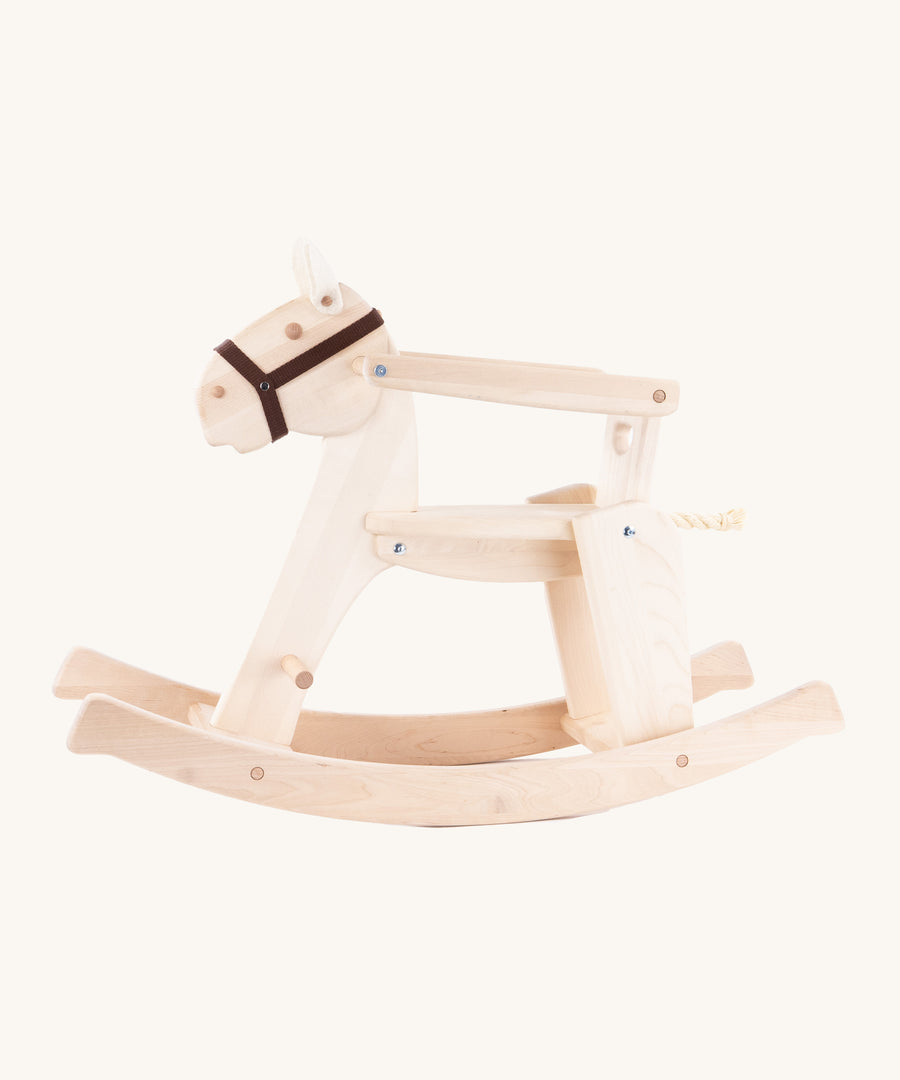 The Bajo Rocking Horse, is a beautiful wooden, classicaly built rocking horse with 2 felt ears, a rope tail and a black head collar. There is also a removable arm rest and a wooden back support to keep little ones secure. The image is taken from the side and is on a cream background