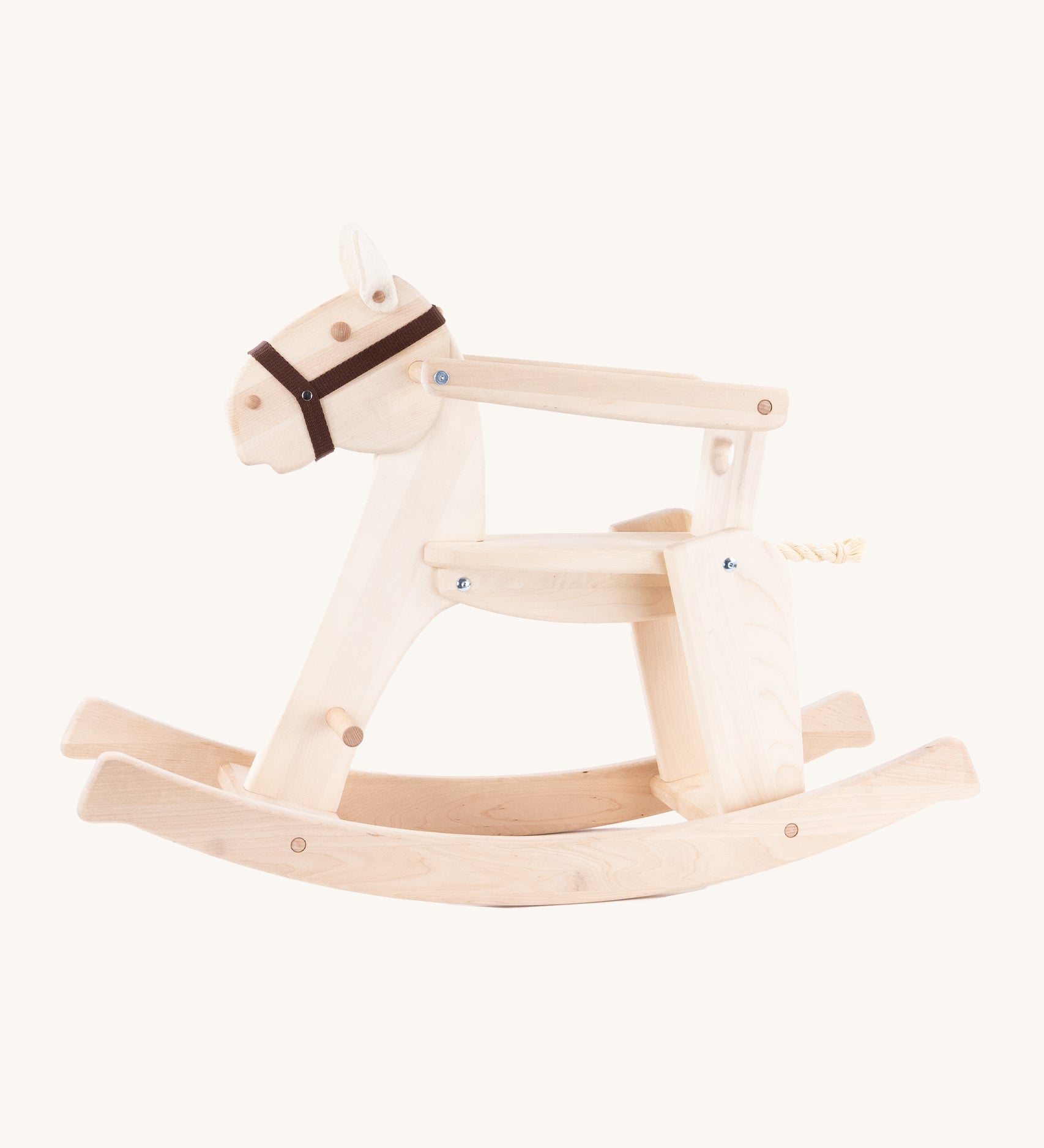 The Bajo Rocking Horse, is a beautiful wooden, classicaly built rocking horse with 2 felt ears, a rope tail and a black head collar. There is also a removable arm rest and a wooden back support to keep little ones secure. The image is taken from the side and is on a cream background