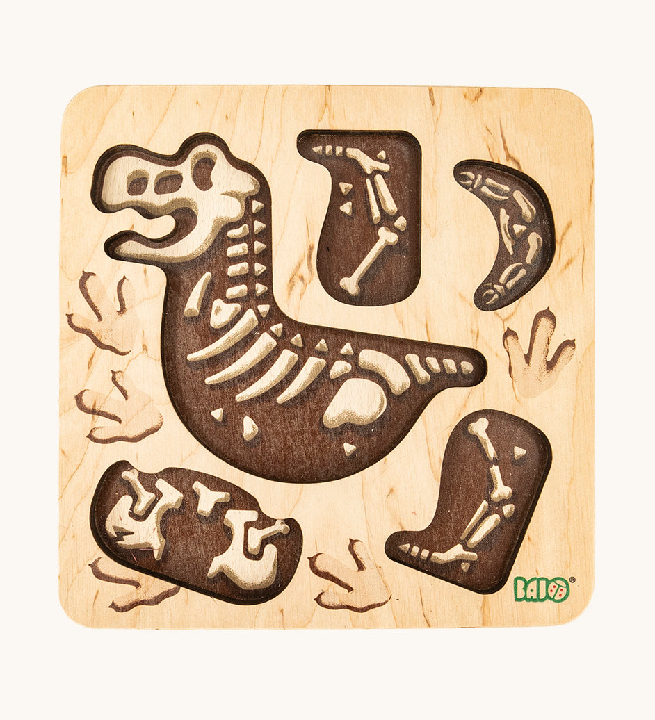 The puzzle board from the Bajo Puzzle & Sorter - Black Oak T-Rex, showing dinosaur bones. On a cream background