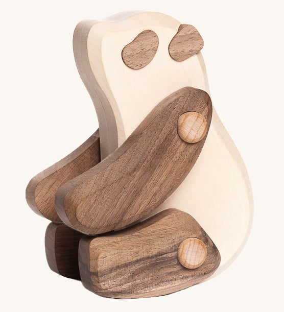 The Tobe Wooden Panda baby toy is sitting down on its back legs. It is a beautifully crated panda in two tone wood, with a white body, dark brown arms and legs, dark brown ears and eye patches. This wonderful wooden toy has movable arms and legs, and is on a cream background