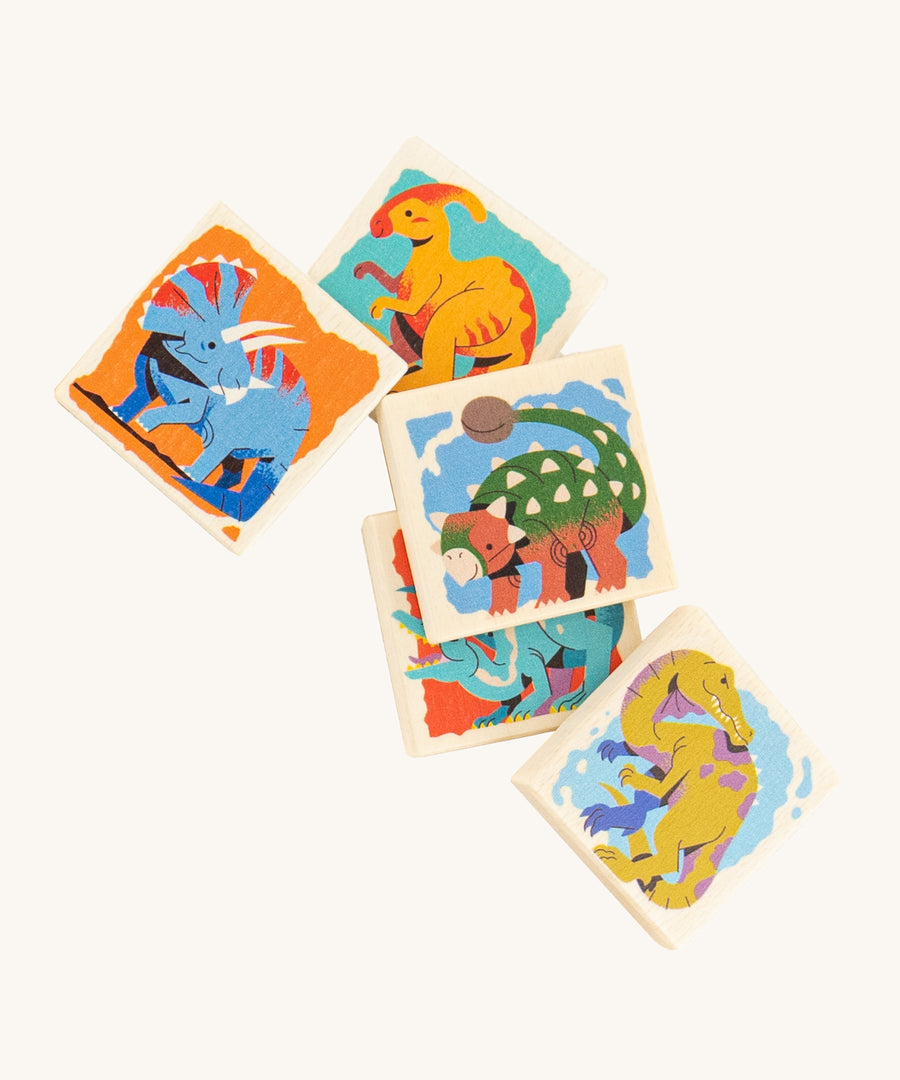 A closer look at 5 square pieces from the kids wooden Bajo Dinosaur Memory Game, showing images of colourful dinosaurs on a cream background