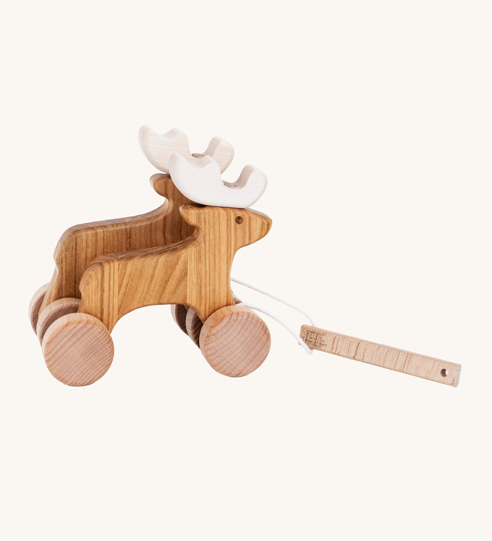 Bajo Wooden Pull Along Jumping Reindeer, is a beautiful children's toy of two natural wooden reindeer with wooden wheels and white antlers, and a wooden rectangle piece to pull along the reindeer which is attached to the reindeer with white string. The image is on a cream background