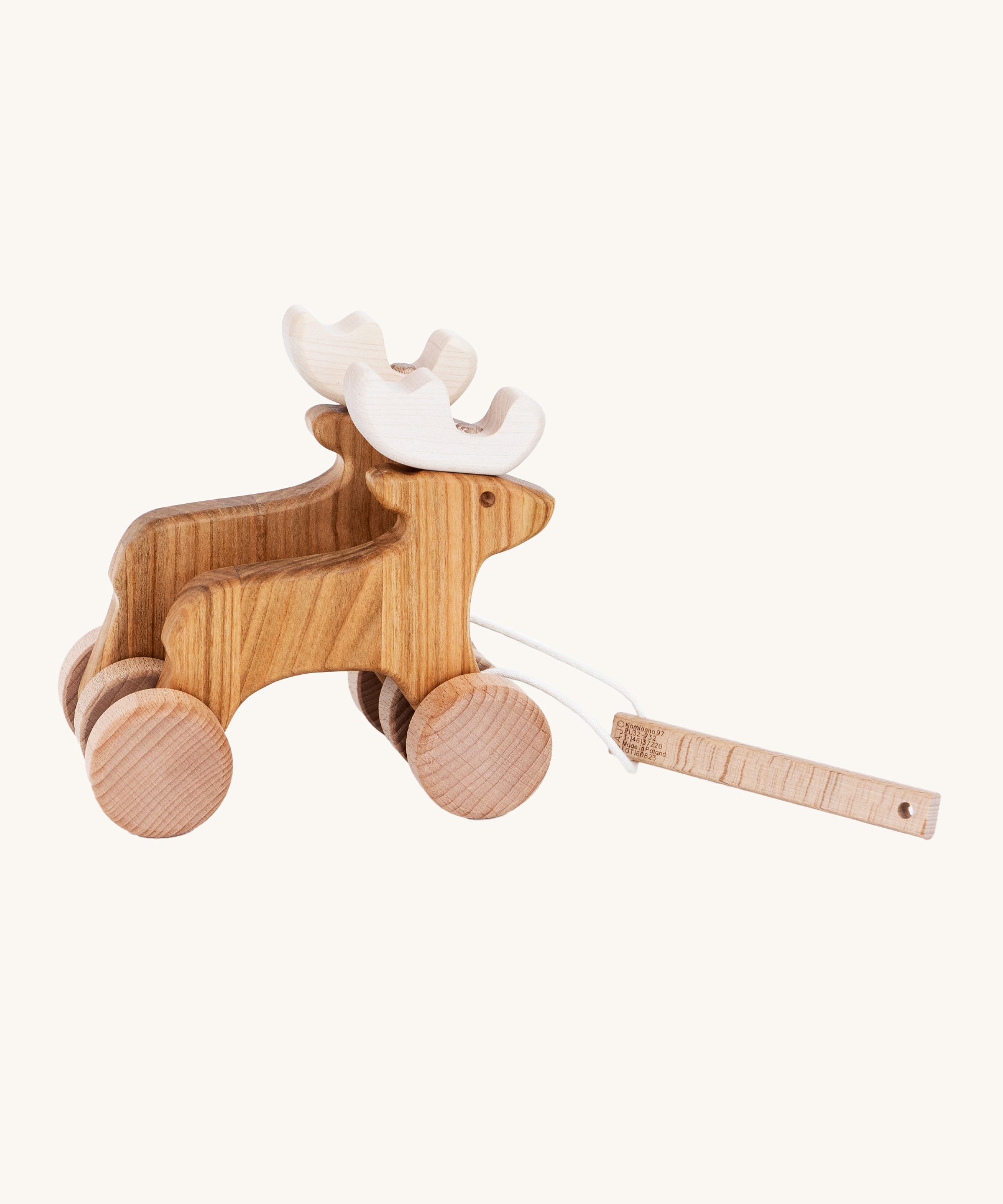 Bajo Wooden Pull Along Jumping Reindeer, is a beautiful children's toy of two natural wooden reindeer with wooden wheels and white antlers, and a wooden rectangle piece to pull along the reindeer which is attached to the reindeer with white string. The image is on a cream background