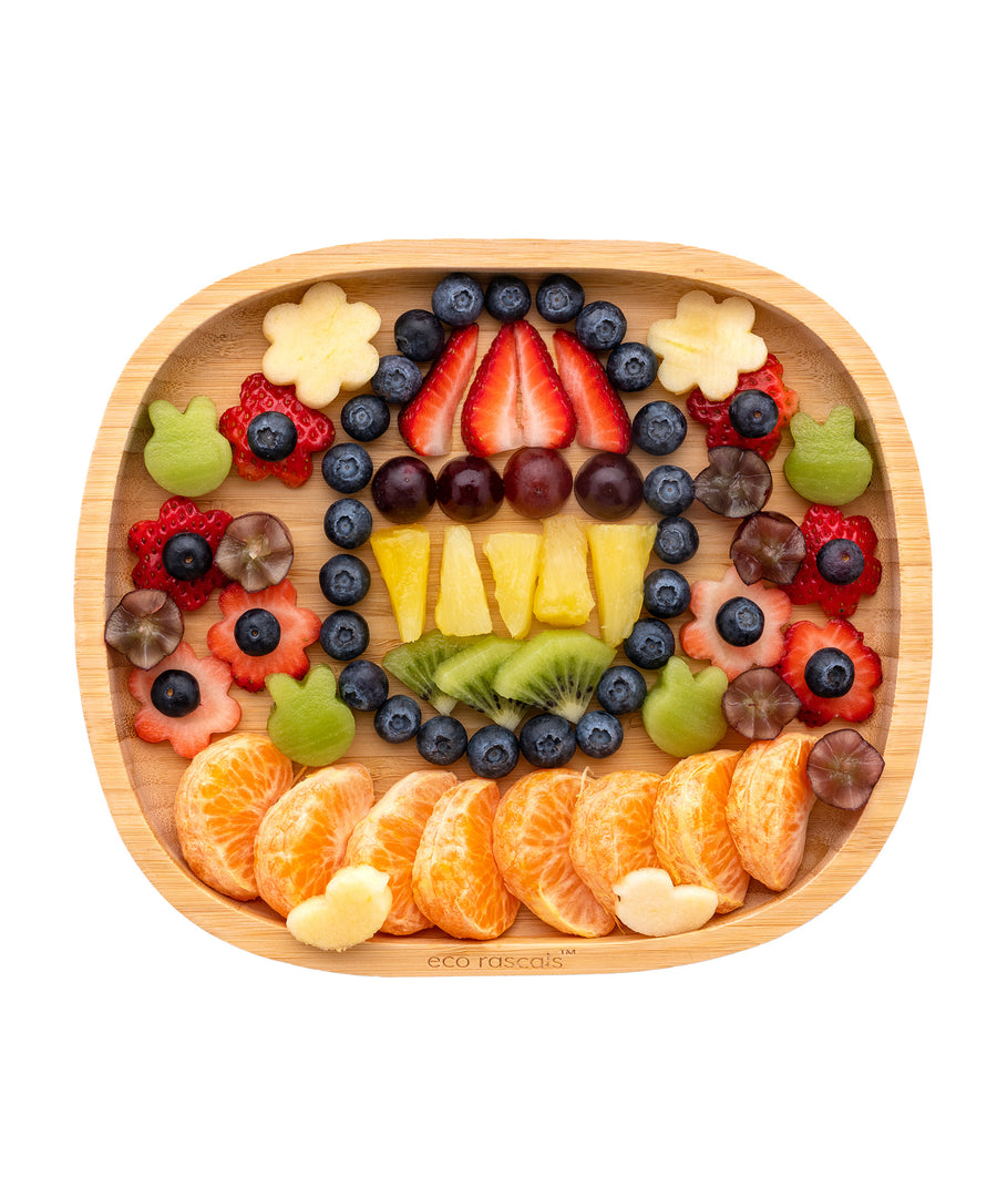 Eco Rascals Rectangle Bamboo Suction Plate, a natural bamboo baby weaning plate filled with a selection of beautifully arranged fruit pieces.