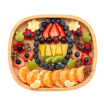 Eco Rascals Rectangle Bamboo Suction Plate, a natural bamboo baby weaning plate filled with a selection of beautifully arranged fruit pieces.