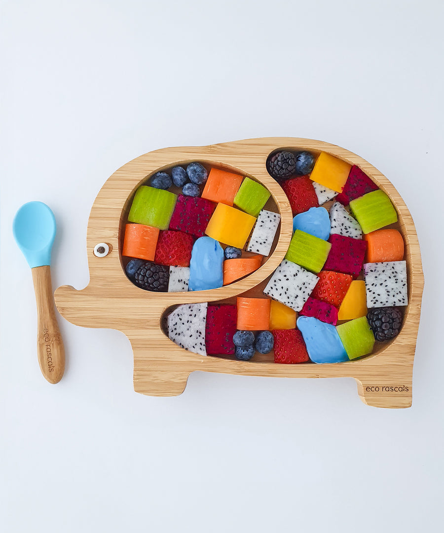 Eco Rascals Elephant Bamboo Suction Plate filled with colourful cubed fruit to look like Elmer the Elephant, with a bamboo and blue silicone baby spoon. 