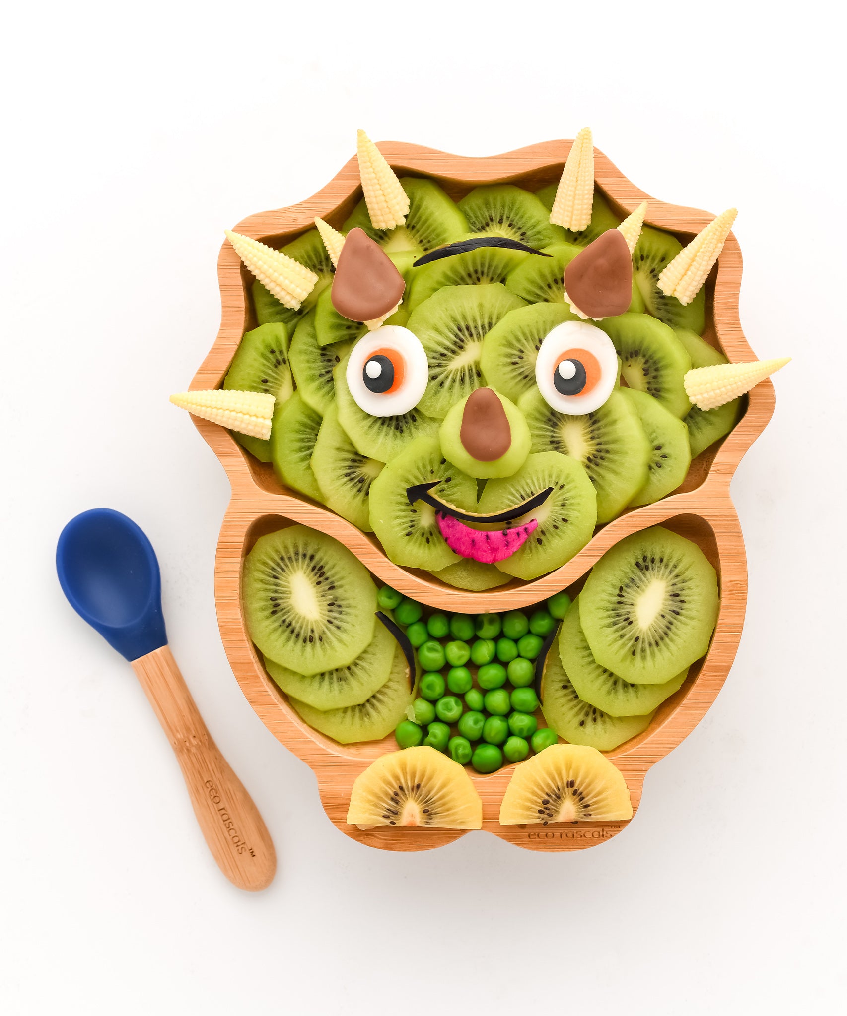 Eco Rascals Dinosaur Bamboo Suction Plate, filled with kiwi slices to look like a triceratops and blue silicone and bamboo baby spoon.