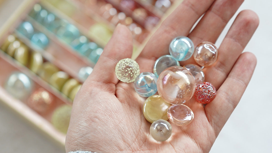 Hand holding some Billies and Co glass marbles of different sizes