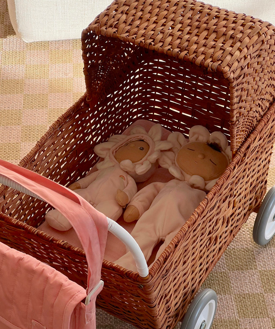 The light cream dinkum dolls lying down in the Olli Ella strolley